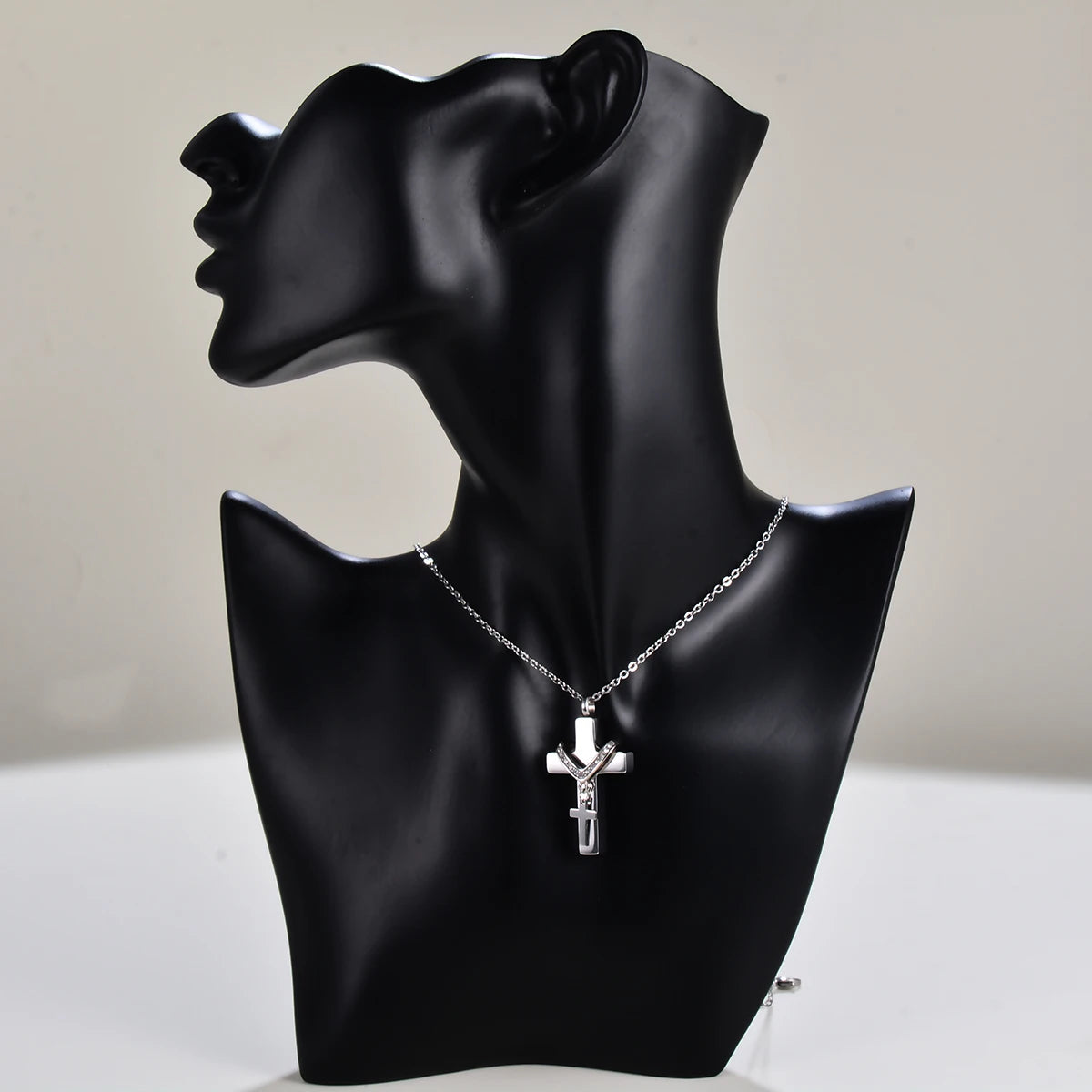 Silver cross cremation necklace displayed on matte black bust for size reference and elegant presentation